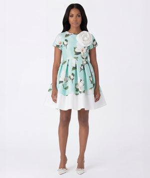 Woman wearing a floral dress with a white flower detail on a white background