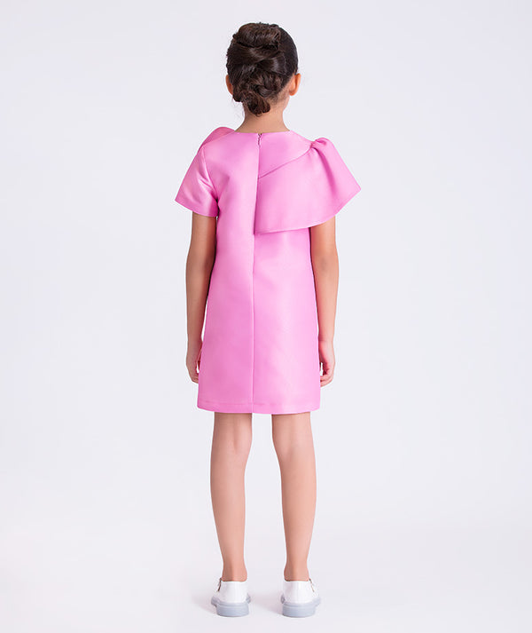 6 years old wearing a pink dress with bow details on a white background