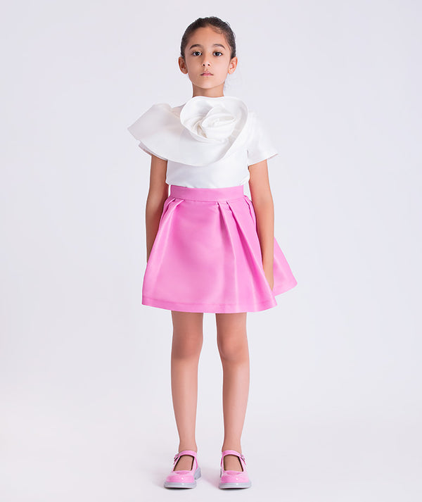 3D flower detail girls outfit worn by a 6-year-old girl, featuring a sculptural white top and flared pink skirt for special occasions.
