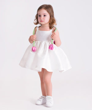 3D flower strap baby girl dress worn by a toddler, featuring wide ribbon straps, straight neckline and a voluminous skirt for special occasions.