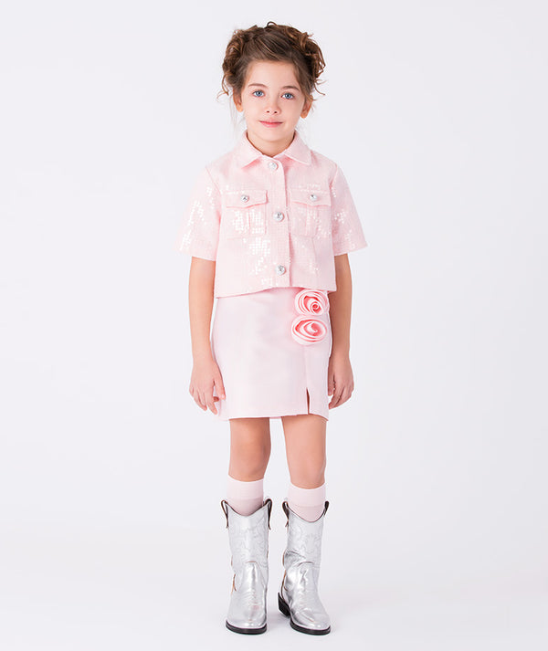 Girl wearing an elegant pink skirt with 3D rose appliqué, styled with a matching jacket for special occasions