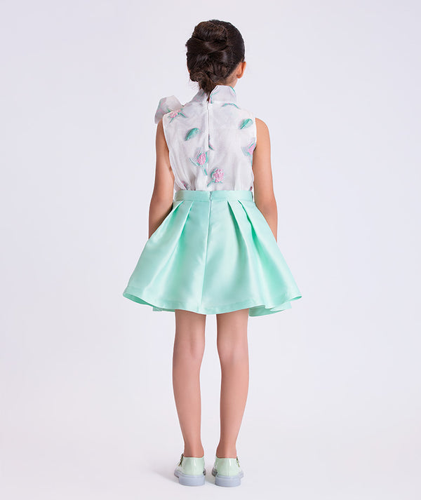 Person wearing a floral blouse and light green skirt on a white background