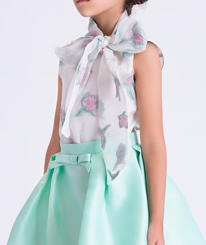 girl wearing a light green dress with a floral scarf on a white background