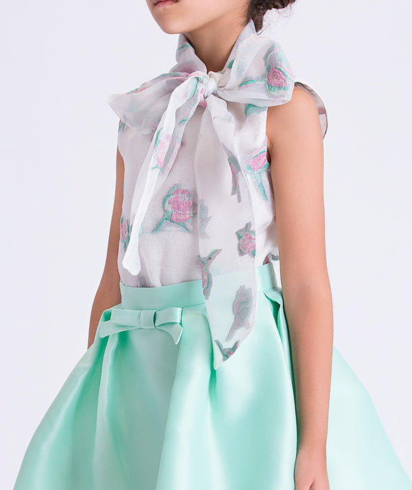 girl wearing a light green dress with a floral scarf on a white background