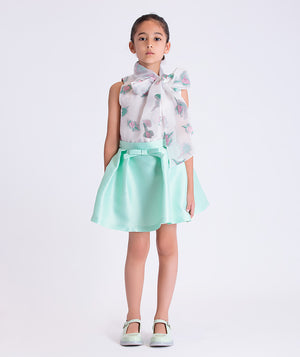 Young girl wearing a floral blouse and light blue skirt on a white background