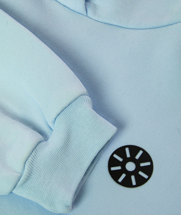 Close-up detail of a light blue girls hoodie highlighting the ribbed sleeve cuff, soft knit fabric, and minimalist chest emblem, designed for everyday wear, school outfits, and casual layering, available in sizes 3–14