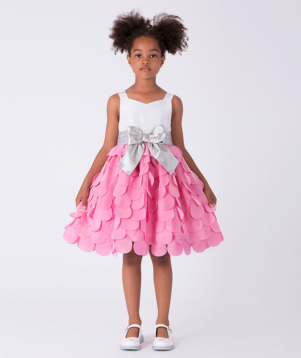7 years old girl wearing a pink dress with a white top and silver bow on a white background
