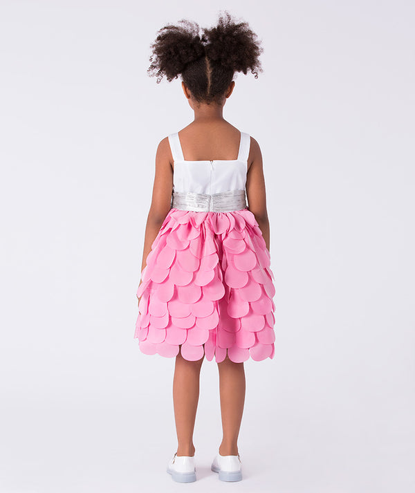 Child wearing a white top and pink ruffled skirt on a white background