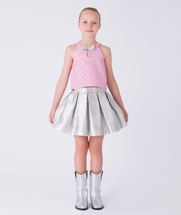 7 years old girl wearing a pink top and silver skirt with matching shoes on a white background