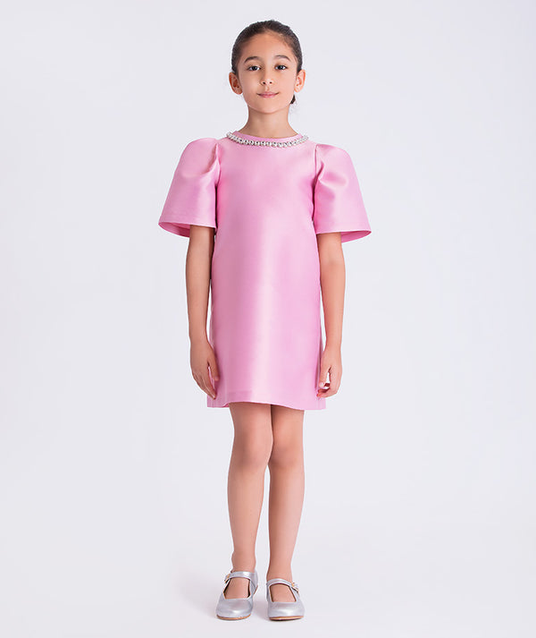Young girl wearing a pink dress with short sleeves on a white background