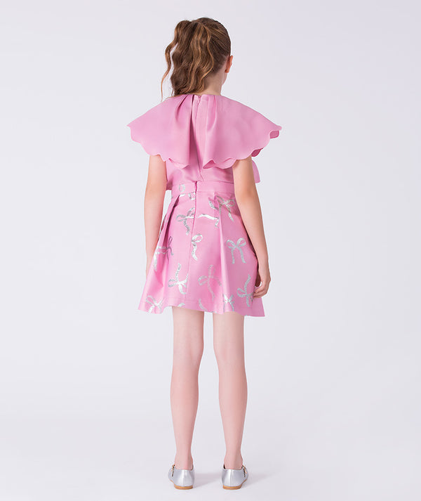 Girl wearing a pink dress with ruffled sleeves on a white background