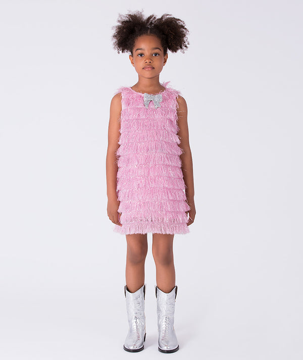 6 years old girl wearing a pink ruffled dress with silver boots on a white background
