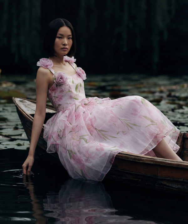 Woman in a floral dress sitting in a boat on a body of water sailing