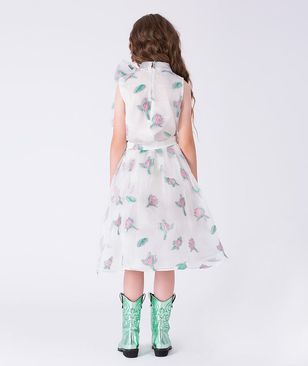 Girl wearing a white dress with floral pattern and green boots on a white background