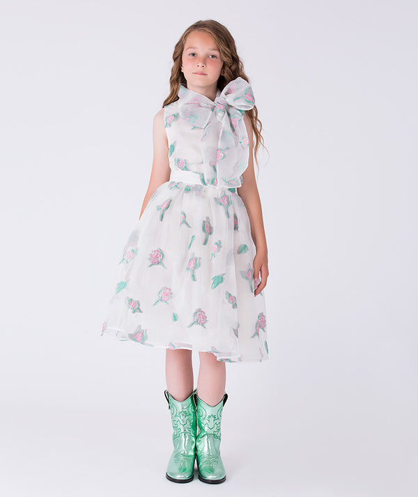 Young girl wearing a floral dress and green boots on a white background