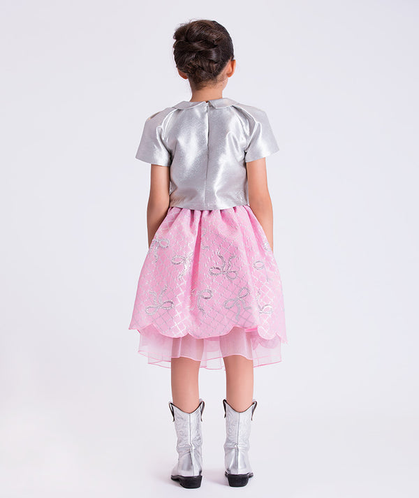 11 years old girl wearing a silver top and pink skirt with butterfly patterns on a white background