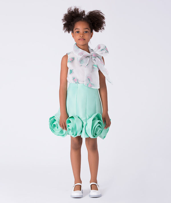 6 years old girl wearing a light green dress with floral details on a white background
