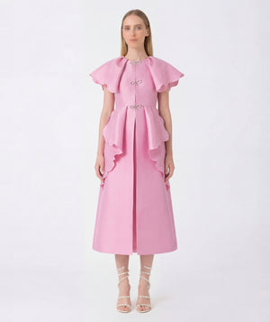 Woman wearing a pink dress with ruffled sleeves on a white background