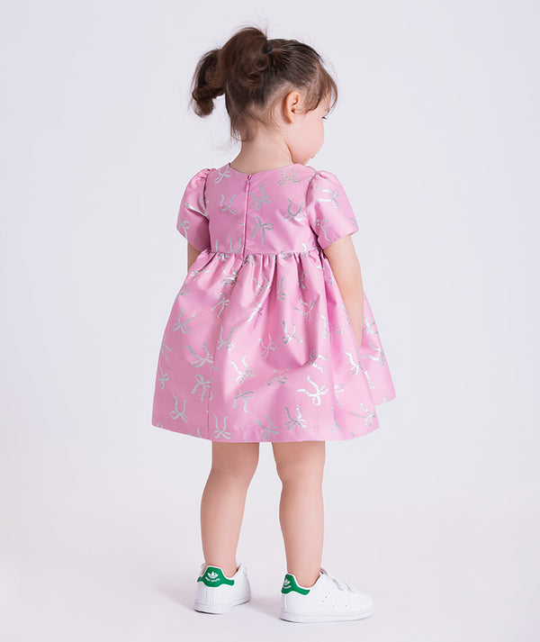baby girl wearing a pink dress with a white background