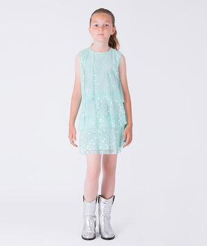 8 years old girl wearing a light blue dress with white polka dots on a white background