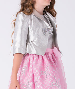 Child wearing a silver jacket with a bow and a pink dress with floral patterns on a white background