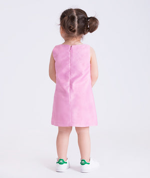 Child wearing a pink dress with white sneakers on a light gray background