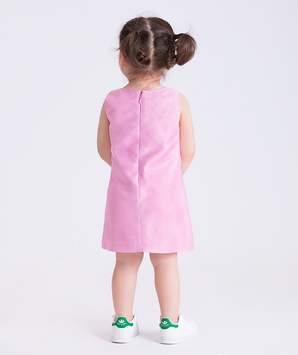 Child wearing a pink dress with white sneakers on a light gray background