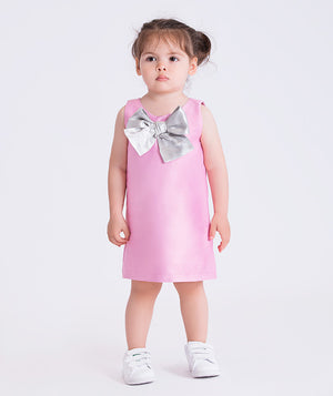 baby girl wearing a pink dress with a large silver bow on a white background