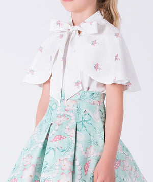 White blouse with floral embroidery and a light blue skirt with flamingo pattern on a white background