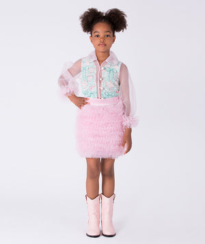 Young girl wearing a light blue top, pink skirt, and pink boots on a white background