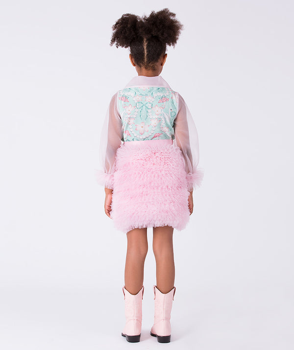 Child wearing a light blue floral top, pink fluffy skirt, and pink cowboy boots on a white background