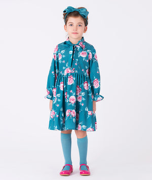 A teal shirt dress adorned with bold pink floral prints, complete with a bow on the front.