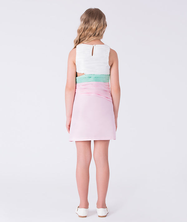 9 years old girl wearing a white top and pink skirt with a green waistband on a white background