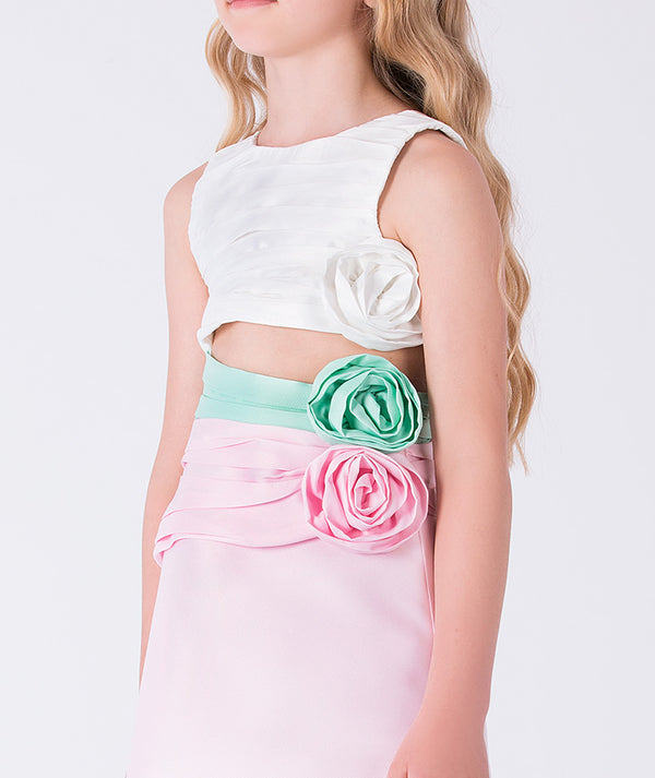 7 years old girl wearing a white top and pink skirt with floral embellishments on a light gray background