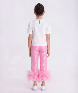 6 years old wearing a white top and pink pants with feathered bottom half on a white background