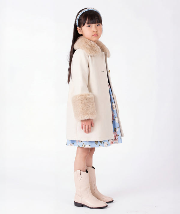 Elegant beige girls winter coat with soft faux fur collar and statement cuffs, styled as refined outerwear for formal celebrations