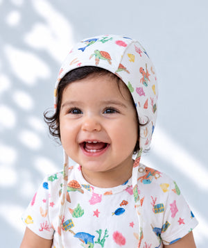 Knitted baby bonnet, cozy newborn accessory shown in a lifestyle photograph, view three.