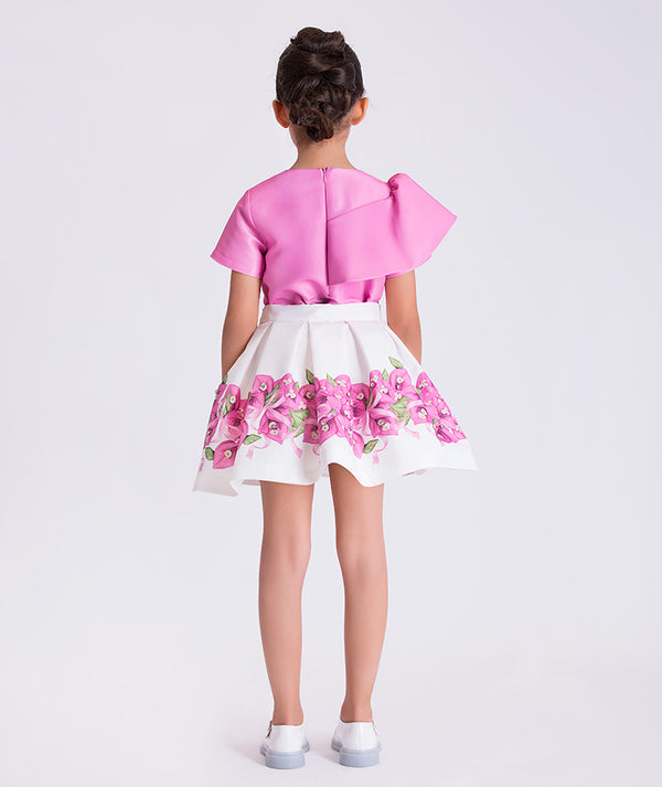Back view of a two-piece girls outfit with structured top and softly flared floral skirt, designed for elegant celebrations.