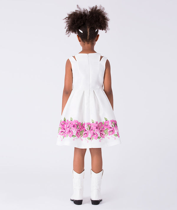 7 years old wearing a white dress with pink floral patterns on a plain background