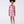 Load image into Gallery viewer, Bougainvillea floral girls jumper worn by a 7-year-old girl, featuring a halter neckline, waist tie and relaxed shorts for summer occasions.
