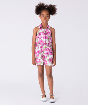 Bougainvillea floral girls jumper worn by a 7-year-old girl, featuring a halter neckline, waist tie and relaxed shorts for summer occasions.