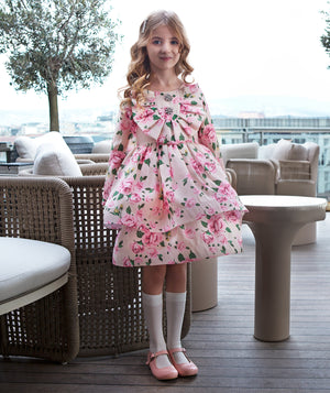 Close-up of the Candy Bow girls’ dress with sparkling crystal embellishments, pink roses and green floral details