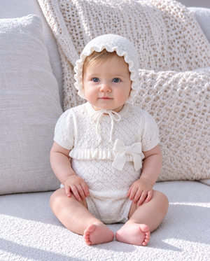 Baby wearing an ivory knitted bonnet in a cozy portrait showcasing soft baby accessories.