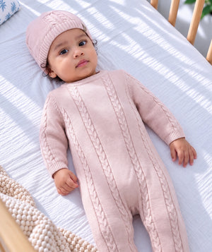 Baby wearing a pink knit outfit, soft baby clothing editorial.
