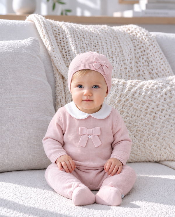 Baby wearing a pink knitted bonnet in a soft knitwear portrait.