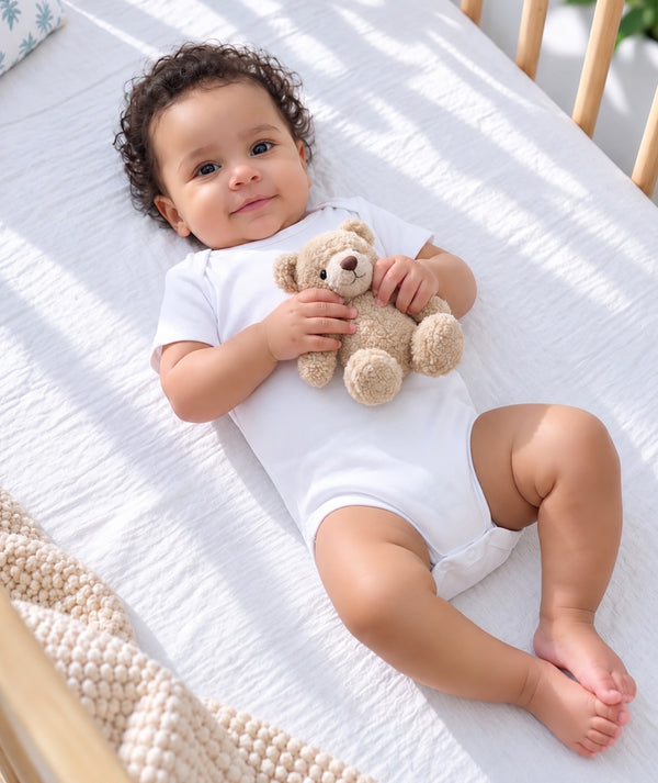 Baby wearing white clothing in a soft newborn editorial portrait.