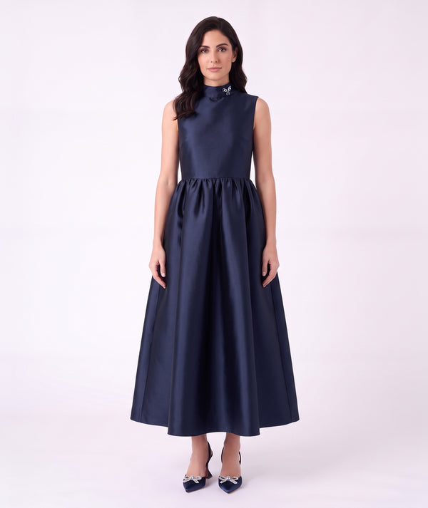 Front view of the Crystal Collar Navy Women’s Dress from Mama Luma’s Suva Maia Collection, featuring a crystal-accented high neckline and full satin skirt.