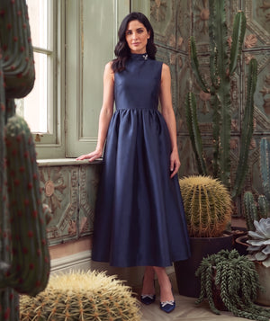 Crystal Collar Navy Women’s maxi dress with a jeweled high neckline and full satin skirt from Mama Luma’s Suva Maia Collection.