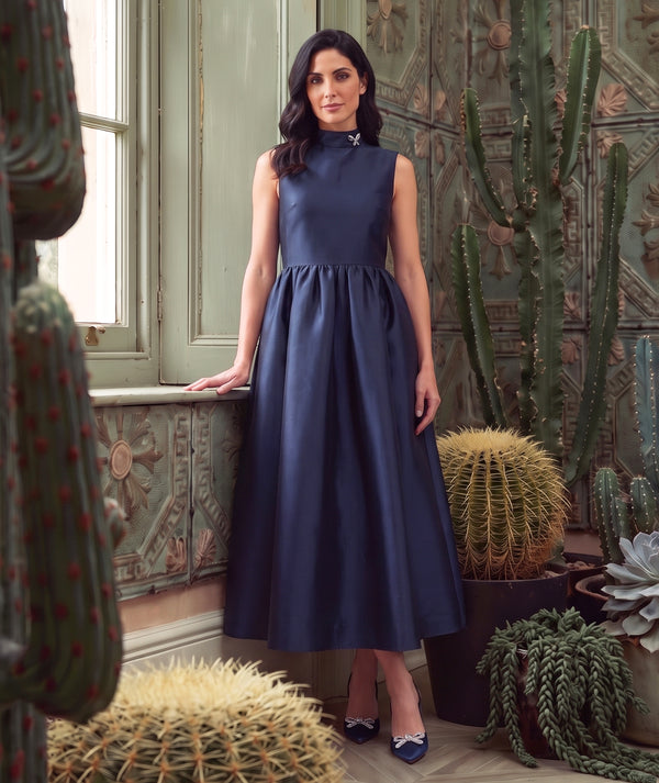 Crystal Collar Navy Women’s maxi dress with a jeweled high neckline and full satin skirt from Mama Luma’s Suva Maia Collection.