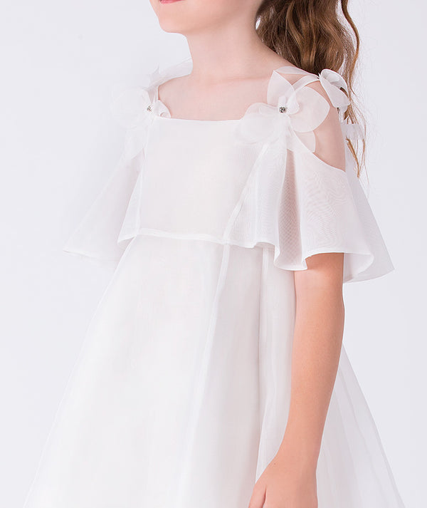 Close-up of crystal-centered floral appliqués on the shoulder straps of a sheer girls occasion dress with delicate craftsmanship